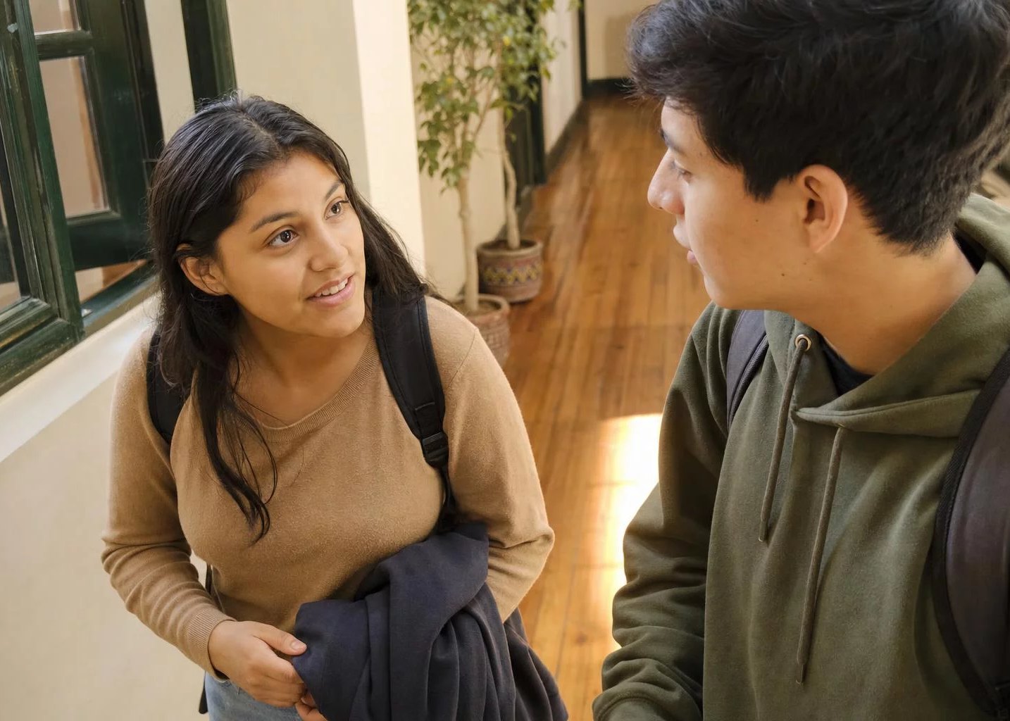 Pasillo de la universidad, con dos estudiantes conversando